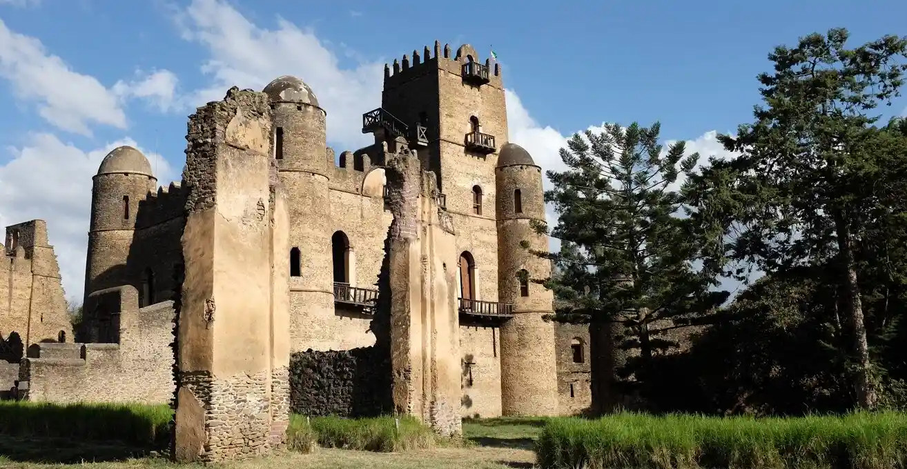 A historic stone tower reflected in a still pool within Gondar's royal complex, Ethiopia