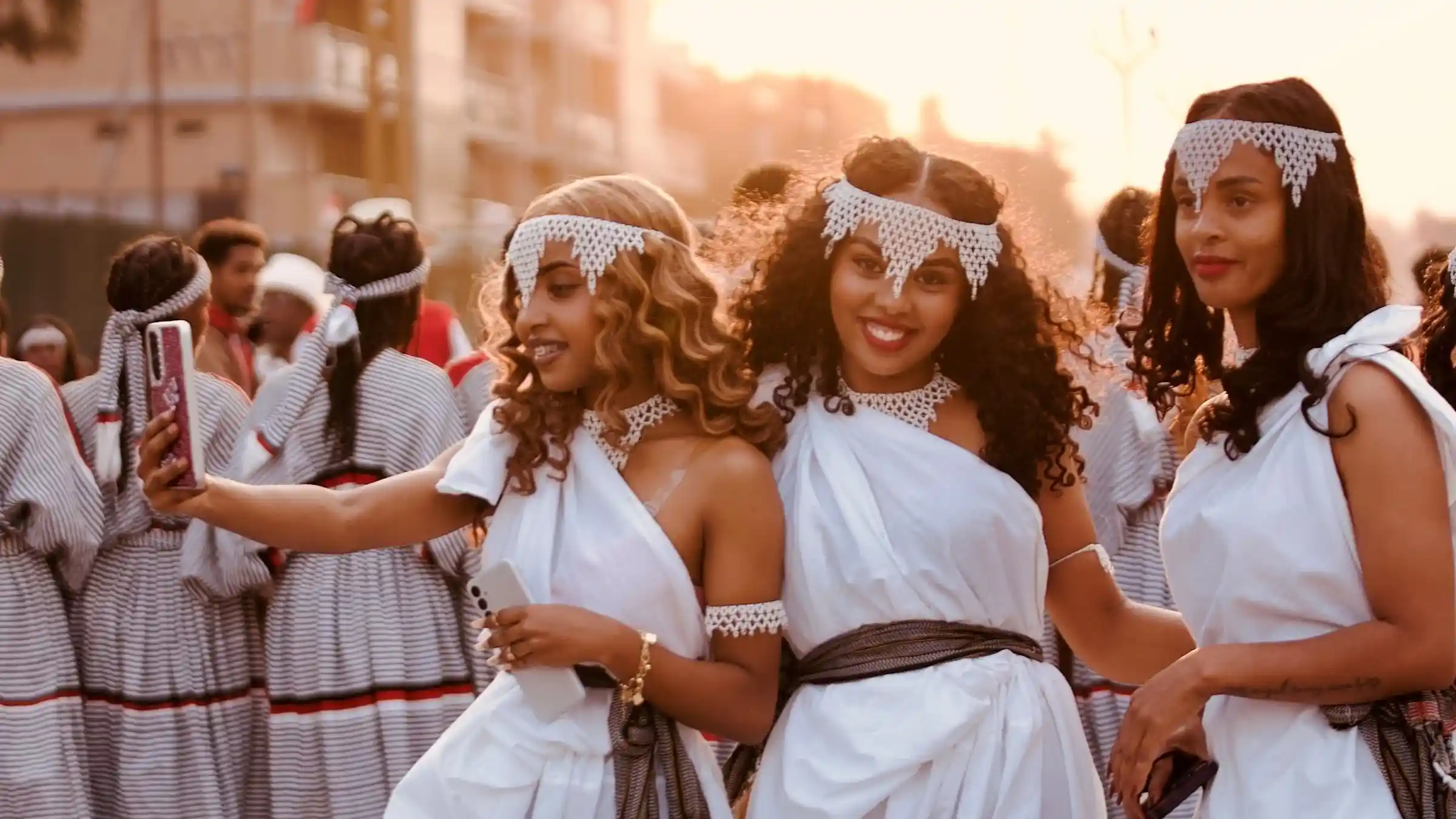 Young women in traditional Oromo dress taking a joyful selfie during the Irreecha celebration