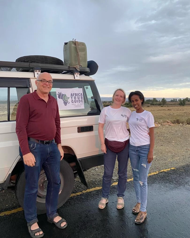 Nigisti Solomon with travelers beside a branded Africa Tour Guide vehicle in the Ethiopian highlands